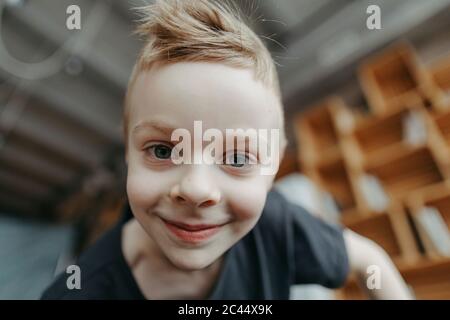 Ritratto in primo piano di un ragazzo biondo sorridente a casa Foto Stock
