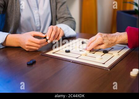 Nipote che gioca a tavola con nonna sul tavolo a casa Foto Stock