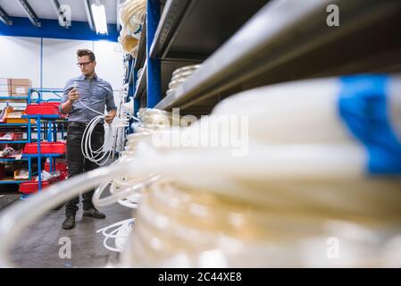 Uomo che esamina un prodotto in una fabbrica Foto Stock