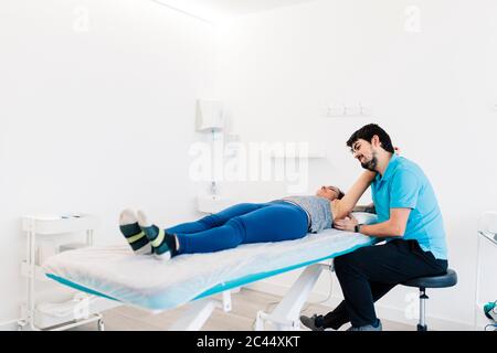 Terapeuta fisica per non vedenti che tratta la mano della donna in clinica Foto Stock