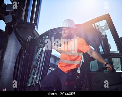 Austria, Tirolo, Brixlegg, Operaio Edile indossando indumenti riflettenti e permanente hardhat dal veicolo Foto Stock