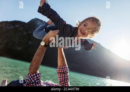 Felice ragazza con armi stese che viene portata dal padre ad Achensee, Stato del Tirolo, Austria Foto Stock