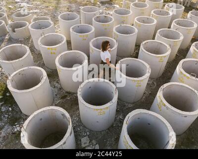 Indonesia, Bali, Donna camminando tra gli anelli di calcestruzzo giacente all'aperto Foto Stock