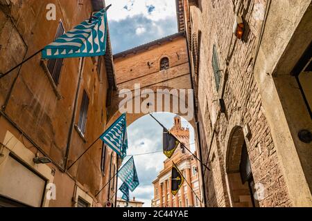 1 giugno 2019 - Foligno, Perugia, Umbria, Italia - un vicolo nel centro di Foligno, con bandiere blu, nere e gialle dei distretti. In basso, Foto Stock