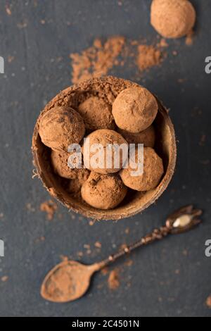 tartufi di cioccolato fondente polvere di cacao in una ciotola di conchiglia di cocco, vista dall'alto, primo piano Foto Stock