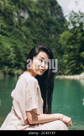 Ritratto di una giovane adulta bella ragazza kazaka sulla riva del fiume su uno sfondo di natura. Foto Stock