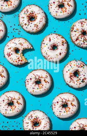 Immagine verticale ad alto angolo di alcune ciambelle fatte in casa con glassa su sfondo blu Foto Stock