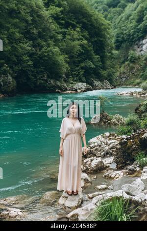 Una giovane adulta bella ragazza kazaka sulla riva del fiume su uno sfondo di natura. Foto Stock