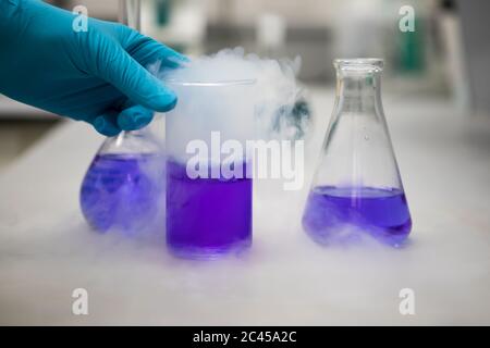Fumare soluzioni chimiche viola in un laboratorio scientifico. Chimica analitica Foto Stock