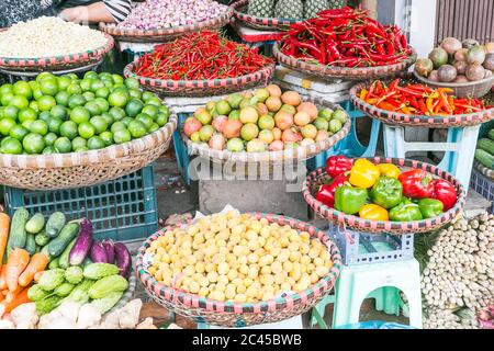 Grandi quantità di verdure in esposizione in un mercato in Hanoi, Vietnam, compresi peperoni, lime, peperoncini, carote e cetrioli Foto Stock
