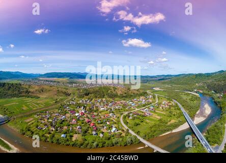 Vista panoramica aerea delle montagne, del fiume di montagna e della città nella valle in primavera. Skyline, splendido paesaggio naturale. Montagne Carpazi. Regno Unito Foto Stock