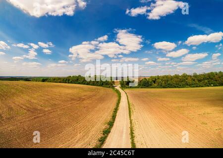 Paesaggio rurale con cielo bellissimo, terreni agricoli, vista aerea. Vista della strada sterrata attraverso il campo arato in primavera Foto Stock