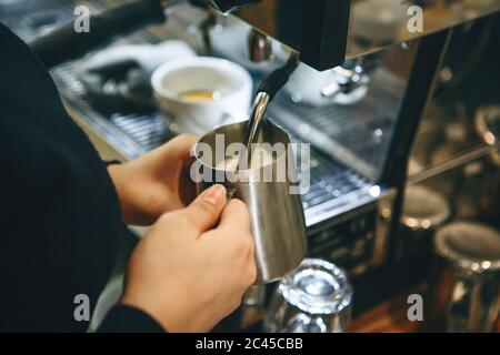 Close-up di un barista preparazione del latte in una macchina da caffè per aggiunta al caffè. Foto Stock