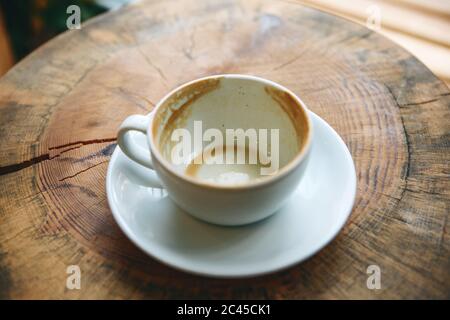 Tazza vuota dopo aver bevuto del caffè su di un tavolo di legno. Concetto per la fine di una riunione o qualcos'altro. Foto Stock