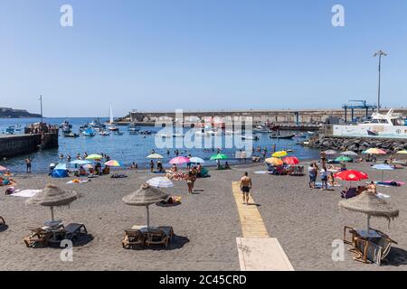 Prendere il sole e rilassarsi sulla spiaggia in una giornata di sole a giugno, Playa San Juan, Tenerife, Isole Canarie, Spagna Foto Stock