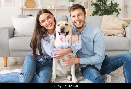 Giovani sposi felici con cane seduto in soggiorno Foto Stock