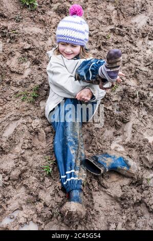La ragazza felice si trova nel fango Foto Stock