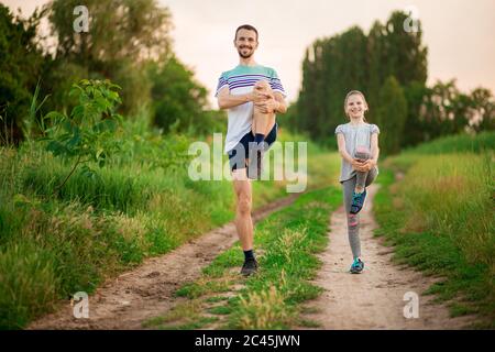 Atletico giovane padre e piccola figlia fare esercizi in stadio. Stile di vita sano Foto Stock