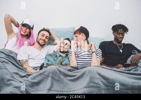 Gruppo di giovani uomini e donne che si stendono in un letto, guardando la macchina fotografica. Foto Stock