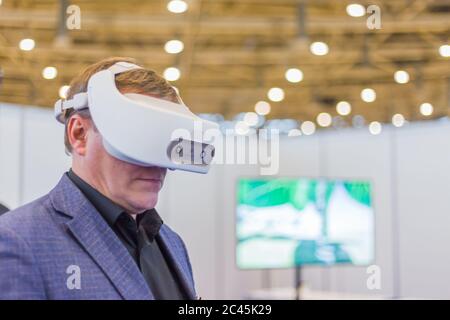 MOSCA, RUSSIA - 1 marzo 2019: VR Exhibition. Uomo che utilizza cuffie per la realtà virtuale e guarda una presentazione video interattiva alla fiera tecnologica Foto Stock