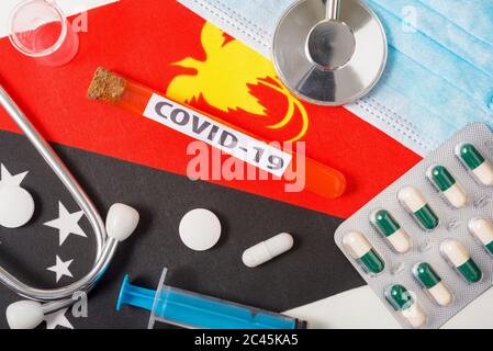 Coronavirus, il concetto COVid-19. Vista dall'alto maschera respiratoria protettiva, stetoscopio, siringa, compresse sulla bandiera di Papua Nuova Guinea. Un nuovo focolaio o Foto Stock