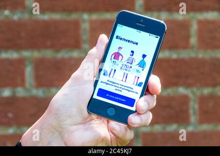Tenendo un iphone con lo schermo, si sfatano StopCovid, l'applicazione francese di tracciamento dei contatti Coronavirus COVID-19. Foto Stock