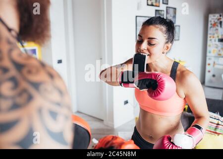 Uomo tatuato con lunghi capelli bruna e donna con lunghi capelli marroni in piedi in casa, pratica kickboxing. Foto Stock