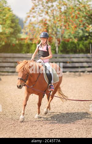 Giovane caucasica che cavalca su un pony, avendo longe linea di guida lezione Foto Stock