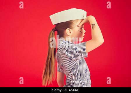 Ritratto di bruna ragazza con top blu e cappello marinaio su sfondo rosso. Foto Stock