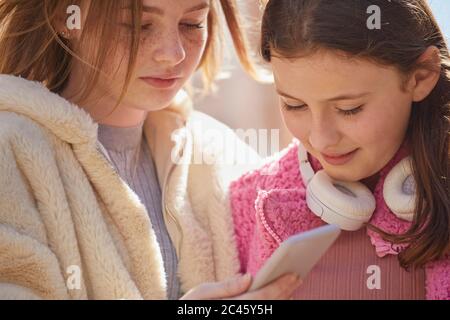 Due ragazze adolescenti in un centro commerciale, controllando i loro telefoni cellulari. Foto Stock