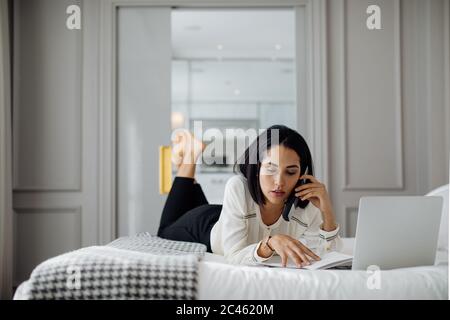 Imprenditrice utilizza lo smartphone e il computer portatile in suite Foto Stock