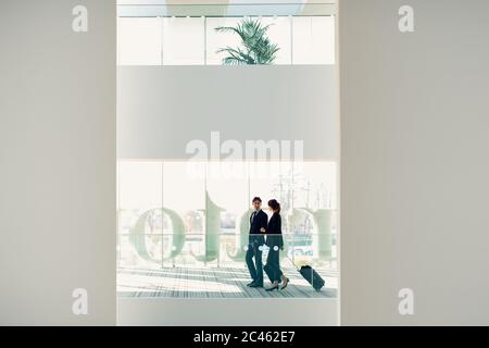 Imprenditore e imprenditrice con Borsoni con ruote nell'edificio dell'hotel Foto Stock