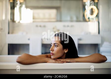 Donna relax nella vasca da bagno in suite Foto Stock