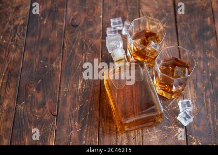 Bottiglia di whisky con due bicchieri posti su un tavolo rustico in legno Foto Stock