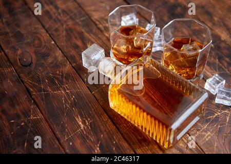 Bottiglia di whisky con due bicchieri posti su un tavolo rustico in legno Foto Stock