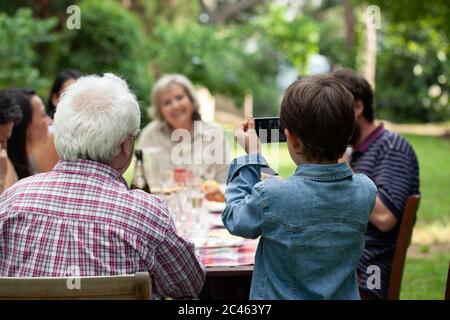 Ragazzo fotografare la famiglia al pasto all'aperto Foto Stock