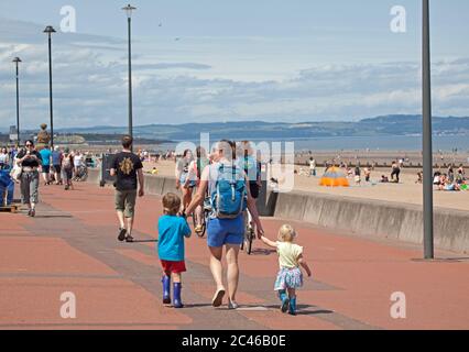 Portobello, Edimburgo, Scozia, Regno Unito. 24 giugno 2020. Il caldo tempo ha portato le famiglie fuori ma il mare non era troppo occupato, molto spazio per mantenere una distanza sociale sulla spiaggia e sul lungomare. Persone su varie tavole da paddle e gonfiabili. Foto Stock