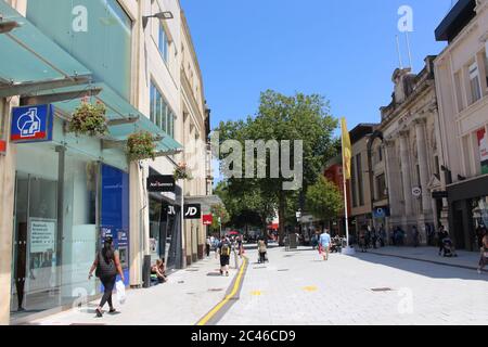 Una fotografia di famiglie e acquirenti su Cardiff Queen Street il giorno più caldo dell'anno, i negozi della settimana sono riaperti. Marcatori di distanza sociali Foto Stock