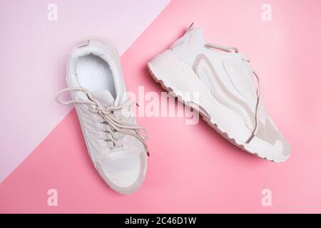 Eleganti sneaker beige da donna su sfondo rosa. Foto Stock