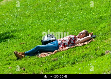 Schull, West Cork, Irlanda. 24 Giugno 2020. Schull si sta crogiolando al sole oggi, dopo una giornata piena di pioggia ieri. Una donna si bagna al sole a Schull. Credit: Notizie dal vivo di AG/Alamy Foto Stock