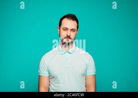 Felice ragazzo caucasico millenario isolato su sfondo blu studio sorridente, positivo giovane uomo in abiti casual. Foto Stock