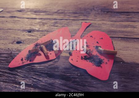 Immagine concettuale di mozziconi di sigarette e bruciando su polmoni rossi isolati su sfondo rustico. Stile pubblicitario del tabacco e del cancro polmonare, guerra medica Foto Stock
