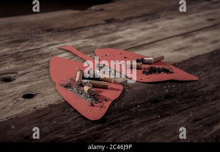 Immagine concettuale di mozziconi di sigarette e bruciando su polmoni rossi isolati su sfondo rustico. Stile pubblicitario del tabacco e del cancro polmonare, guerra medica Foto Stock