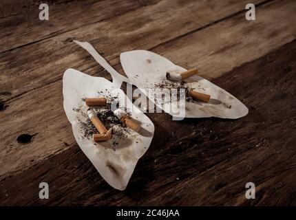 Immagine concettuale di mozziconi di sigarette e bruciando su polmoni sporchi isolati su sfondo rustico. Stile di pubblicità del tabacco e del cancro polmonare, medico w Foto Stock