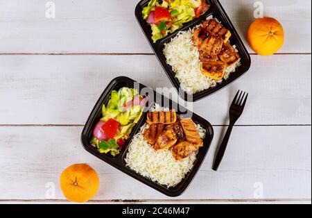 Pasto pronto da mangiare su contenitore con forchetta, bevanda e arancia. Foto Stock
