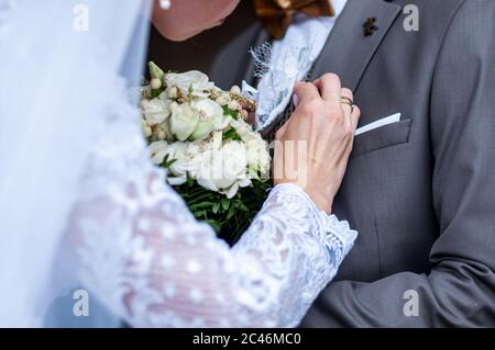 Sposa che indossa bonbonniere sulla giacca da grooms Foto Stock