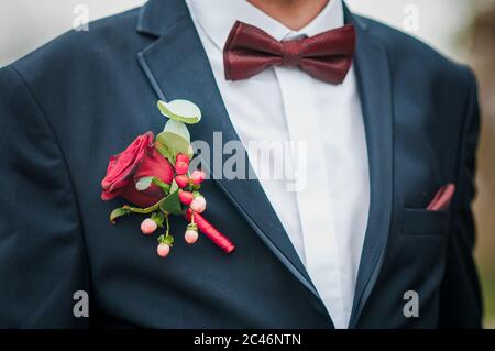 Viscere rosse scure sul collo degli inguini e rosa rossa sulla giacca Foto Stock
