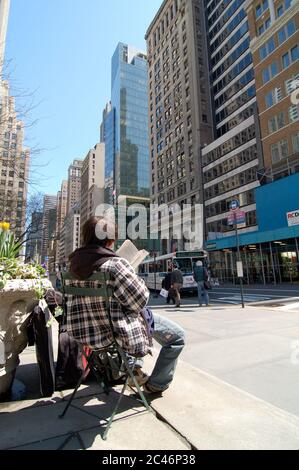 Manhattan, New York, USA - 26 Marzo 2009 : Vista posteriore di un uomo che legge e che gode di un libro nel mezzo del quartiere di Manhattan, questo può essere usato come l Foto Stock