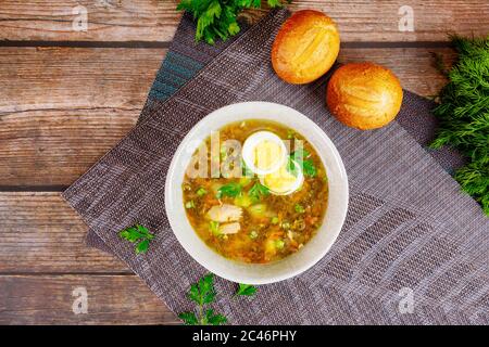 Zuppa di verdure sane con uova e panini croccanti su sfondo di legno. Foto Stock