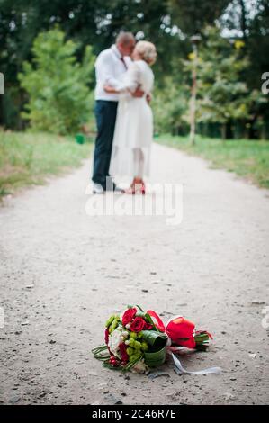 Bouquet di fiori che giace sulla strada e un paio di persone sullo sfondo Foto Stock